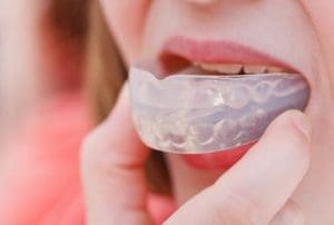Teen sports girl putting a mouth guard in her mouth.