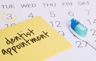 Note written upon dentist appointment on a table with a toothbrush.