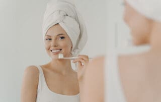 Female patient posing with toothbrush in hand, looking happy and satisfied.