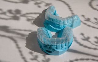 Pair of Invisalign aligners positioned on fake teeth models.