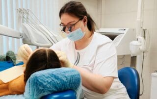 Dentist wearing glasses with attached lenses, providing dental treatment to a patient.