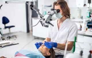 Dentist examining a patient's teeth through a microscope.