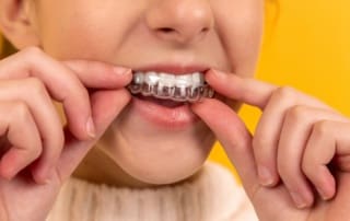 Child carefully adjusting aligners on her teeth.
