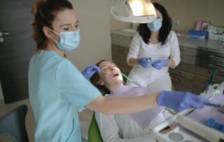 Two dentists administering treatment to a patient lying straight.