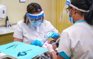 Two female dentists providing dental treatment to a patient.