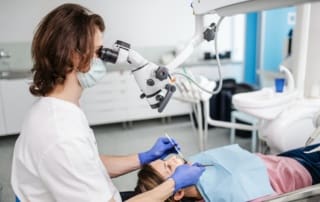 Female dentist using a microscope to examine a patient's teeth.